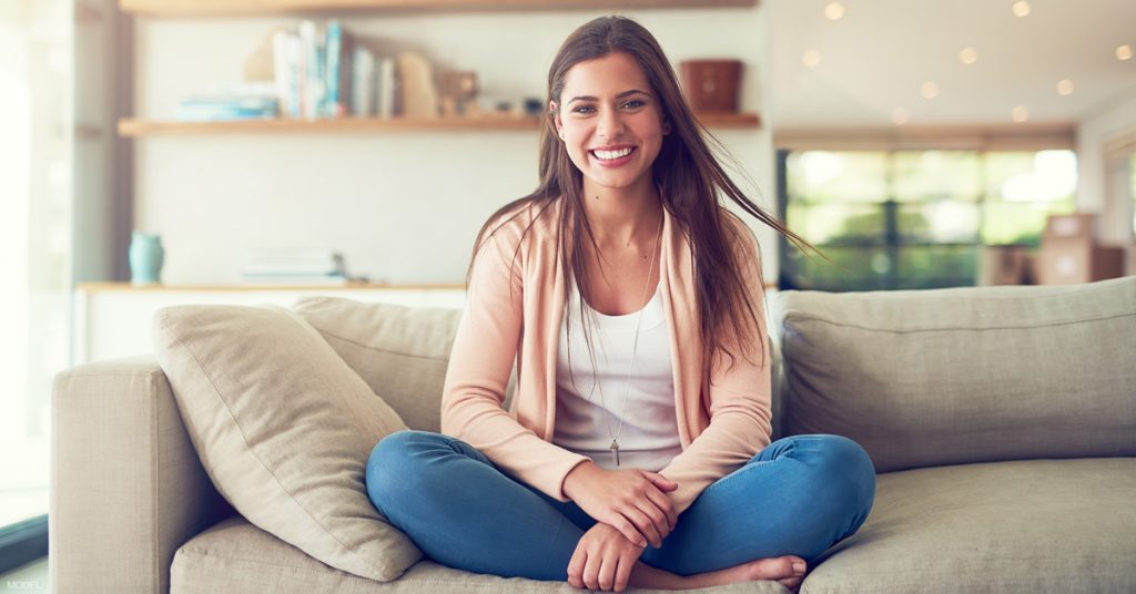 Beautiful woman sitting on couch in living room while taking care of herself at home